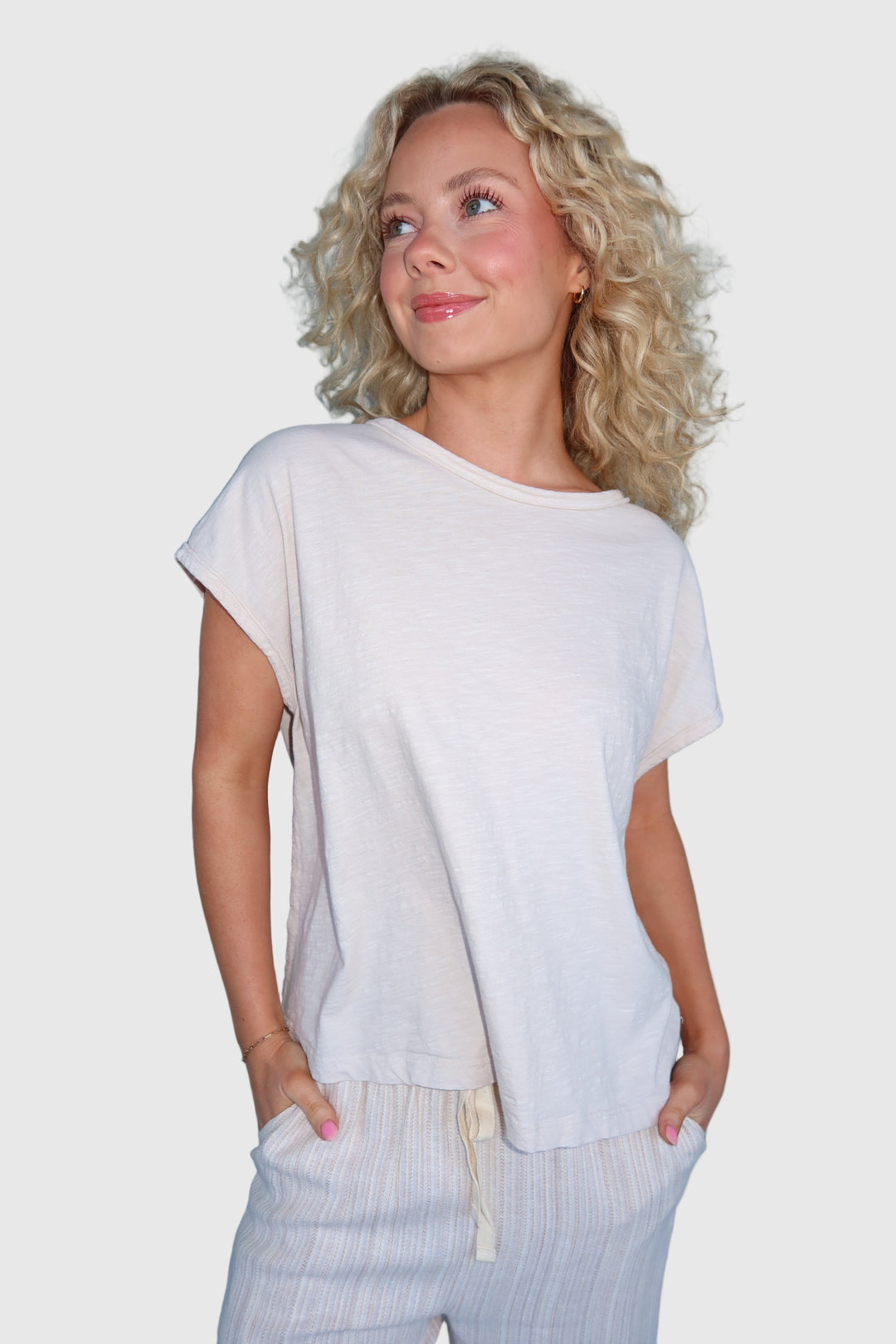 A woman wearing a Boxy Cap Sleeve Tee with a relaxed fit, paired with light-colored trousers