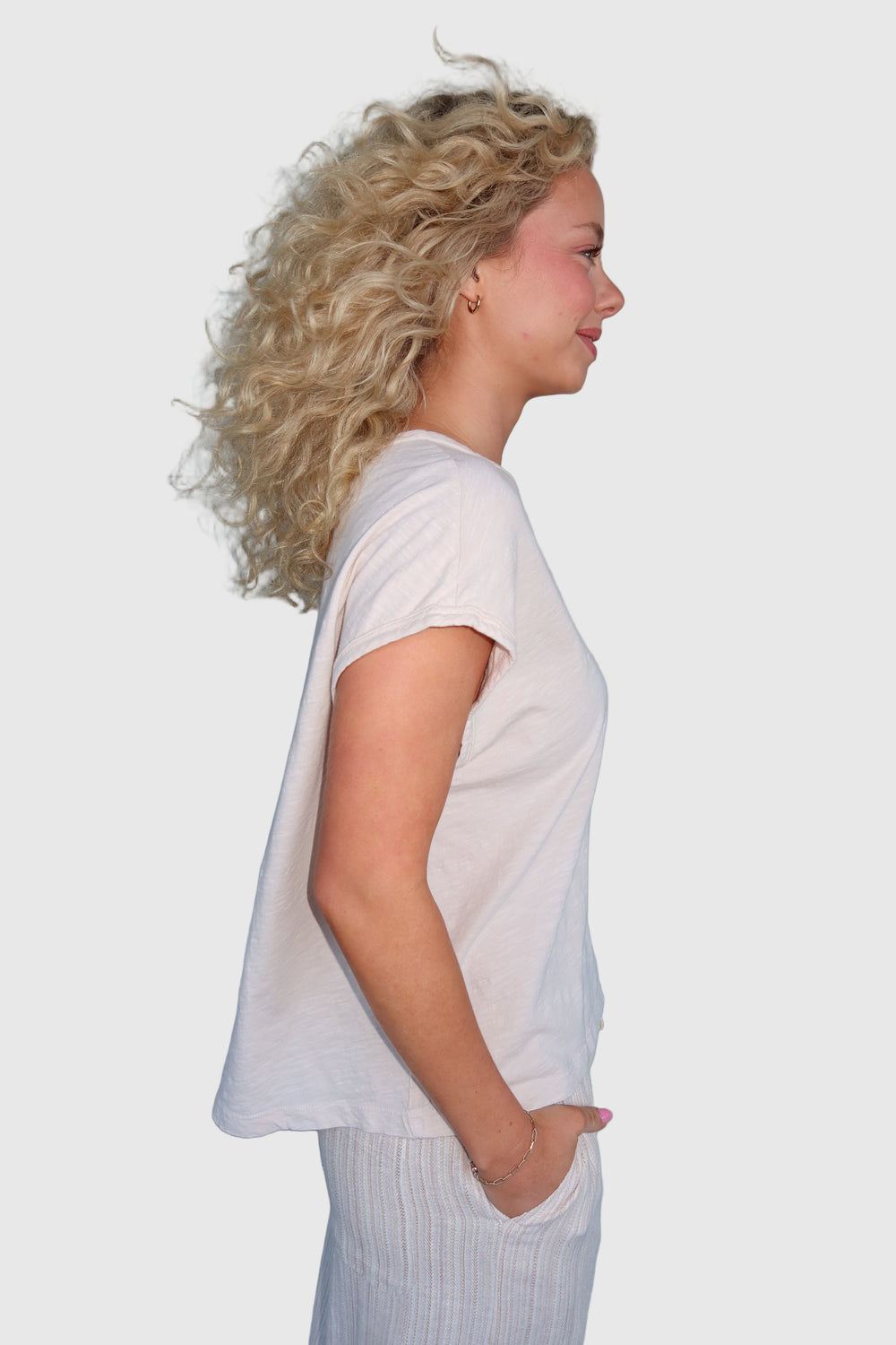 A woman wearing a Boxy Cap Sleeve Tee with a relaxed fit, paired with light-colored trousers