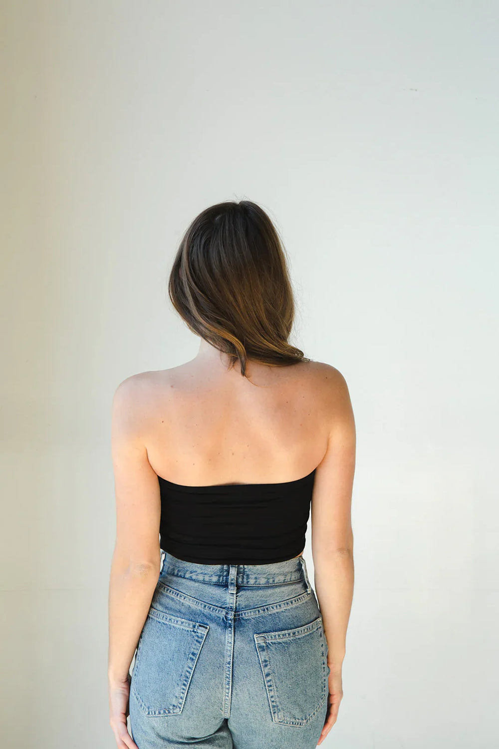 Product shot of NŪD Apparel Hunter Double Layer Bandeau in black paired with  high rise denim, back view.