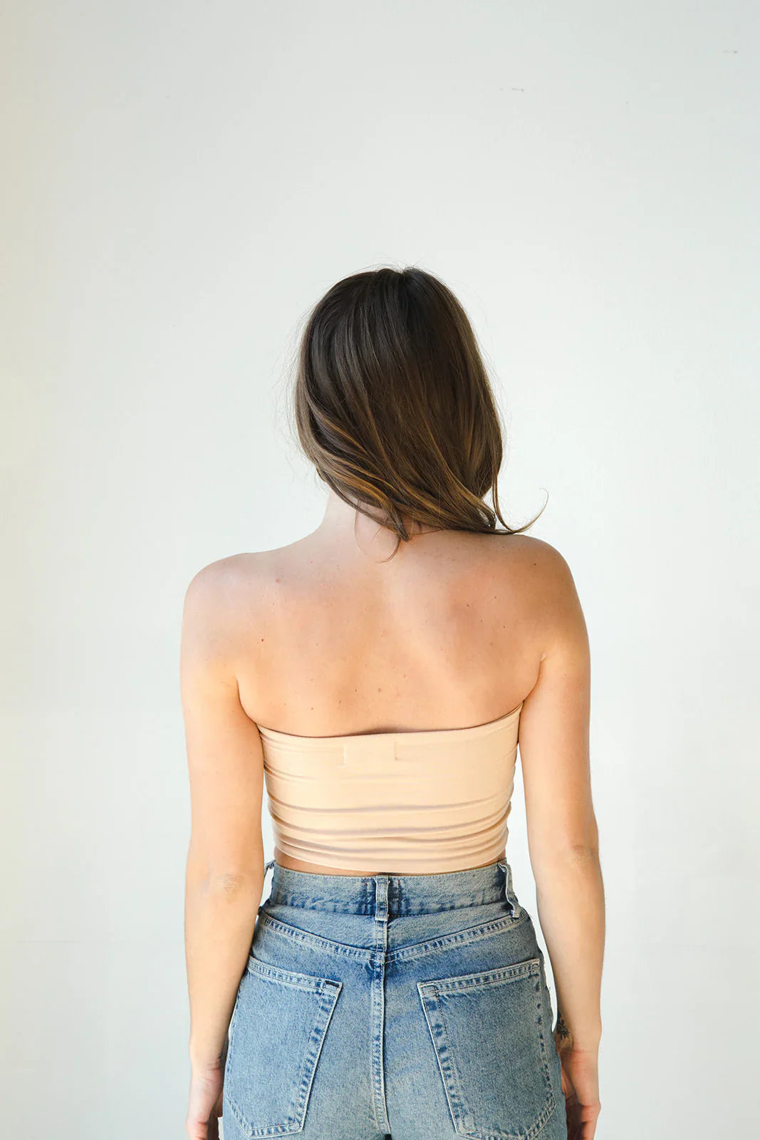 Product shot of NŪD Apparel Hunter Double Layer Bandeau in light nude paired with high rise denim, back view.