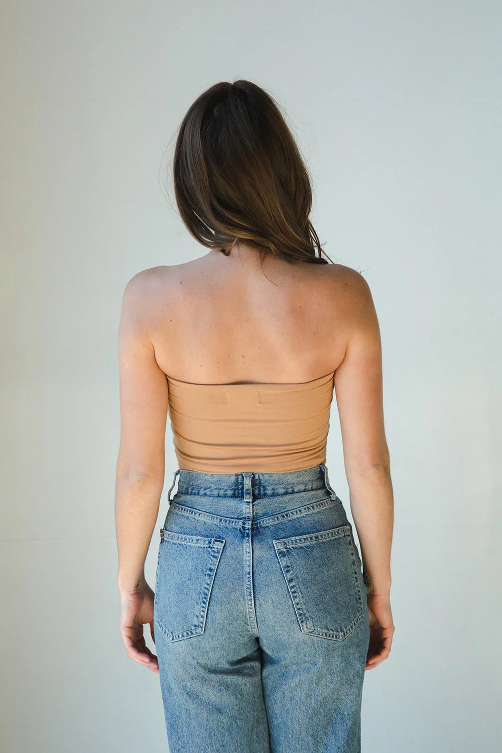 Product shot of NŪD Apparel Hunter Double Layer Bandeau in medium nude paired with high rise denim, back view.