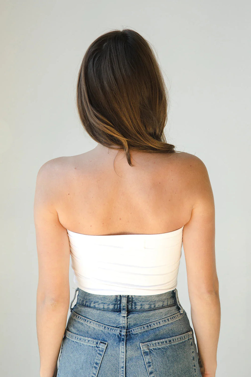 Product shot of NŪD Apparel Hunter Double Layer Bandeau in white paired with  high rise denim, back view.