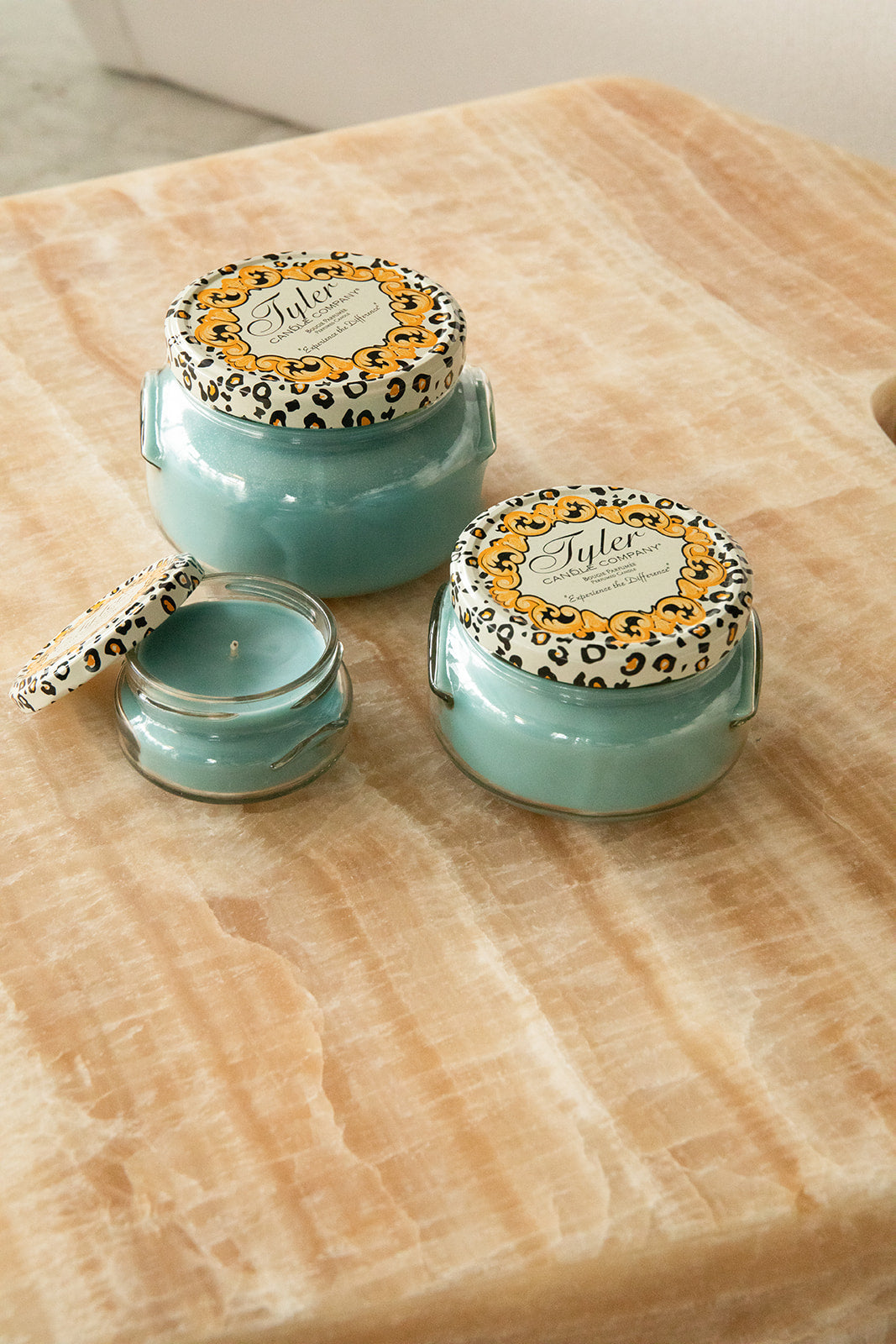 Product shot of Tyler Candle Company candles in 22oz, 11oz, and 3.4oz in scent resort.
