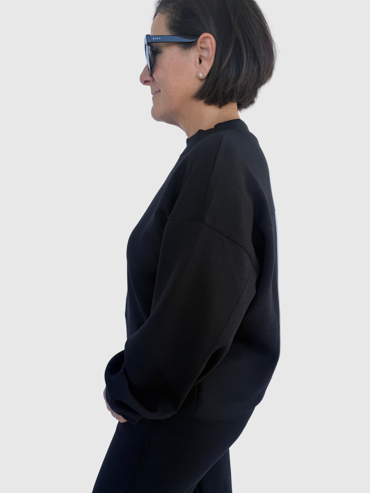 Person wearing a black sweatshirt against a light background