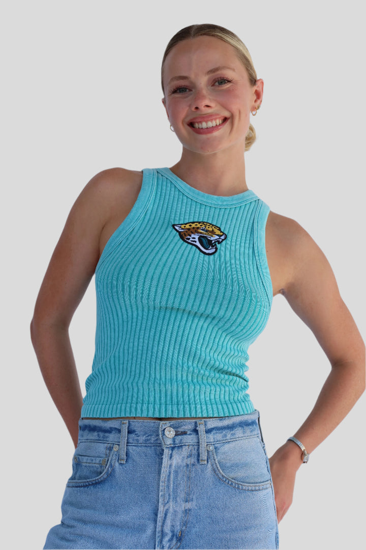 Woman wearing a turquoise ribbed tank top with a Jaguar logo and denim against a white background.