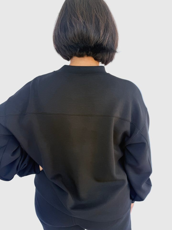 Person wearing a black top against a light background