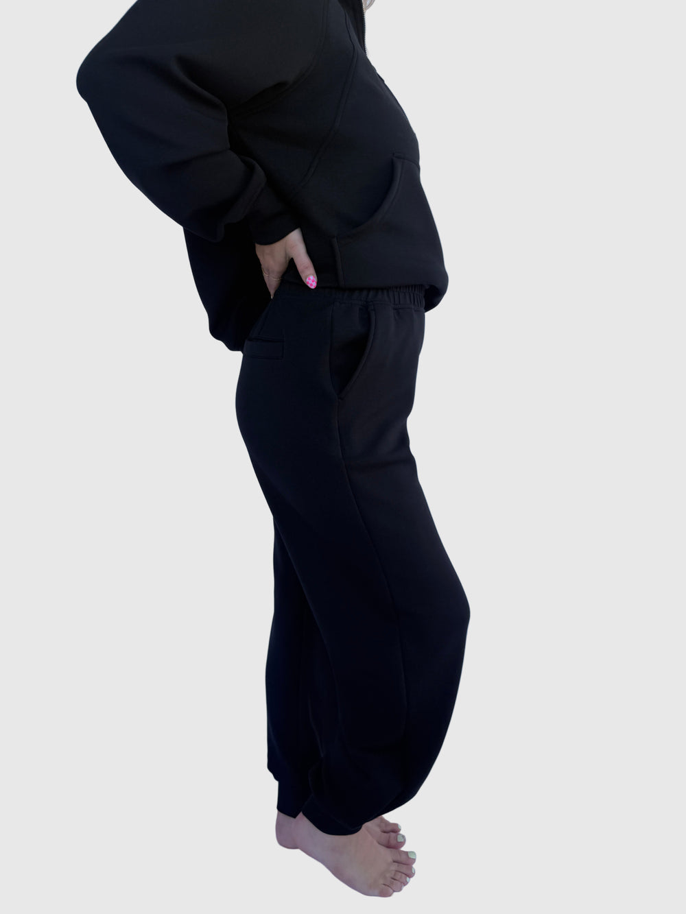 Person wearing black pants against a light background