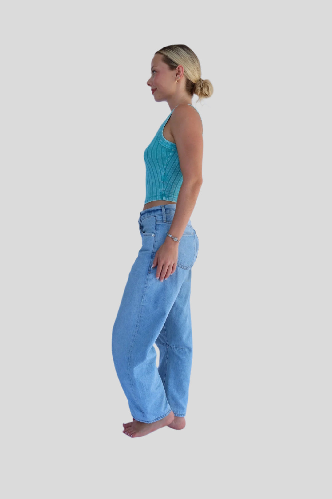 Woman wearing a turquoise top and light blue jeans against a white background