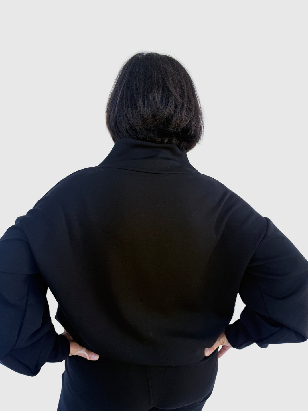 Person wearing a black outfit against a light background