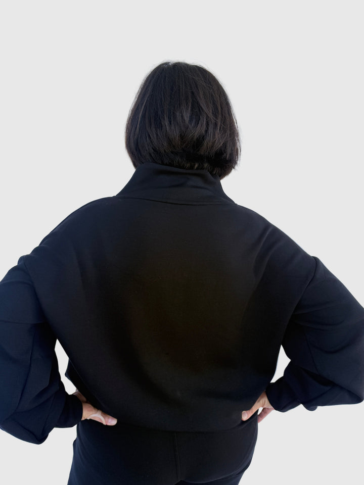 Person wearing a black outfit against a light background