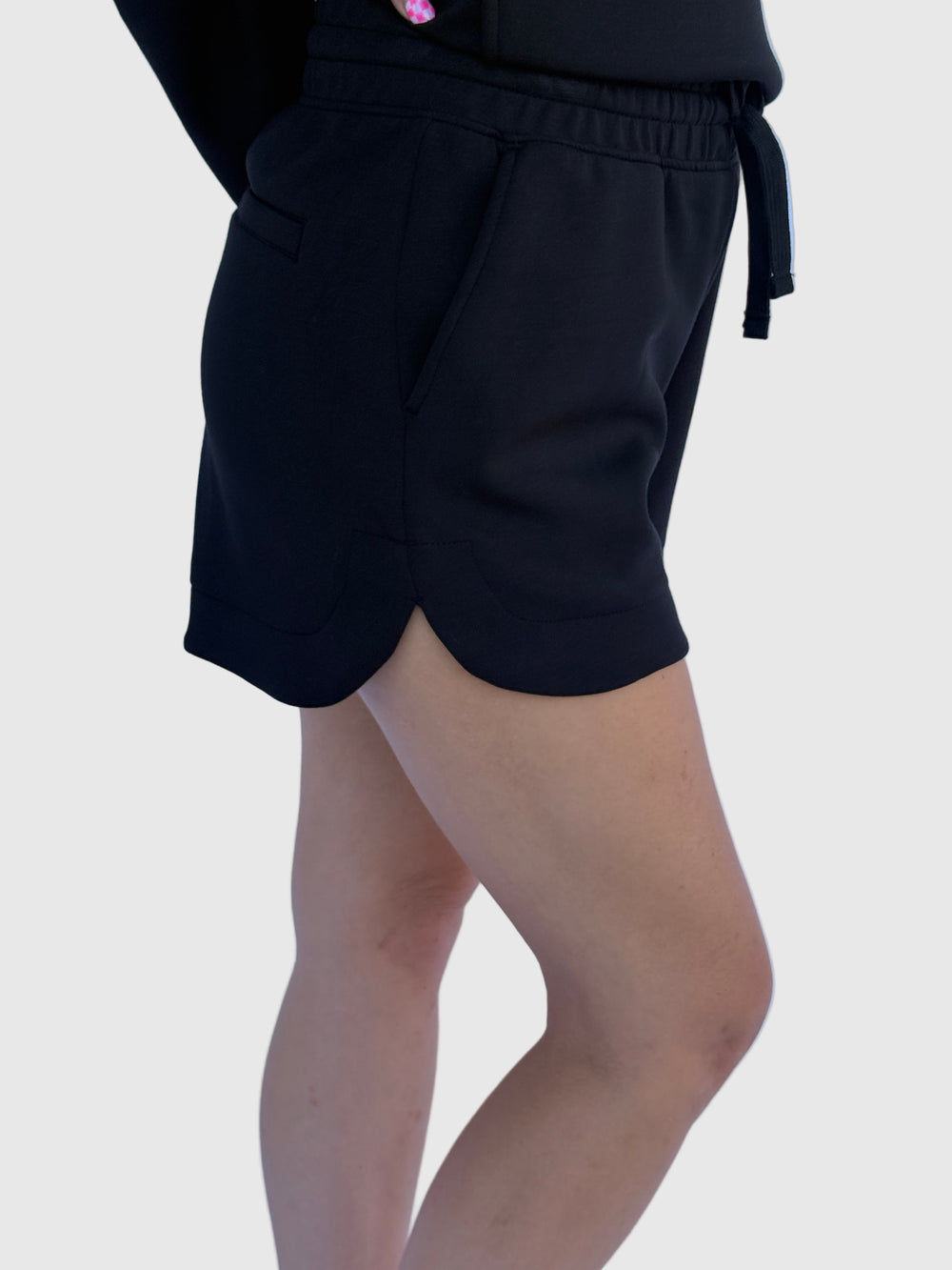 Person wearing black shorts with a light background
