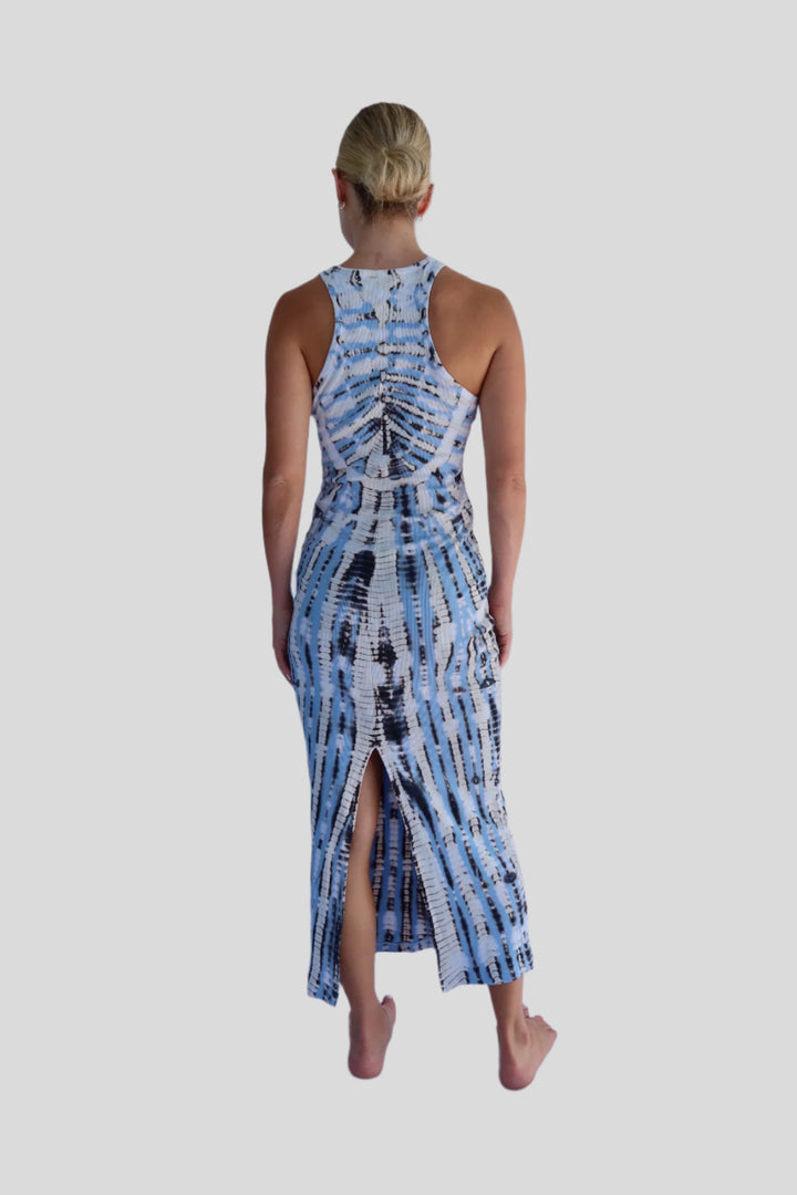 Woman wearing a blue and white patterned dress with a slit on a light blue background
