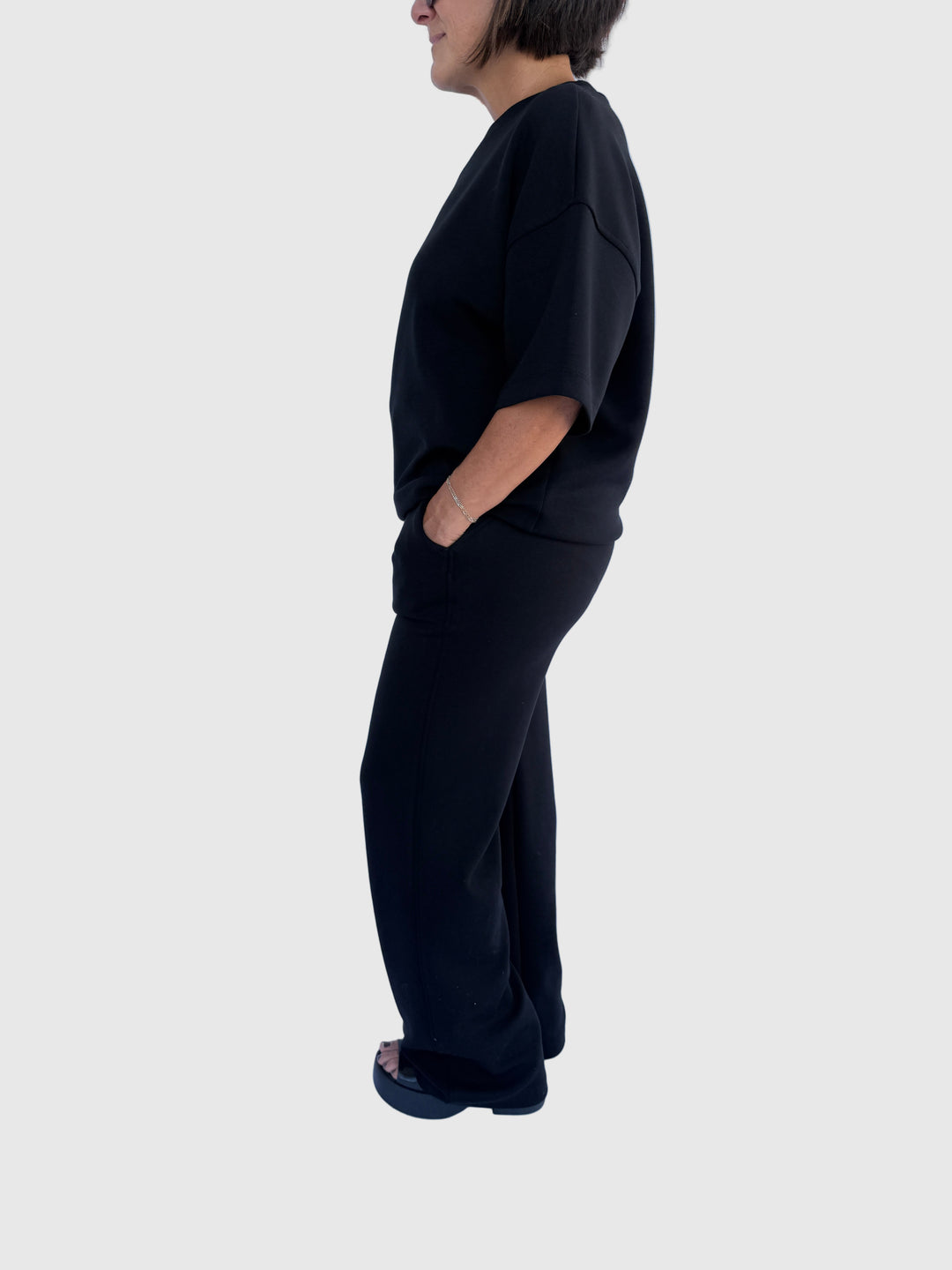 Person wearing a black outfit against a light background