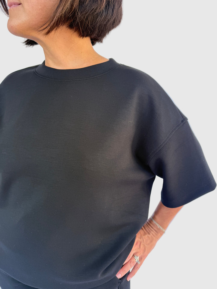 Person wearing a black top against a light background