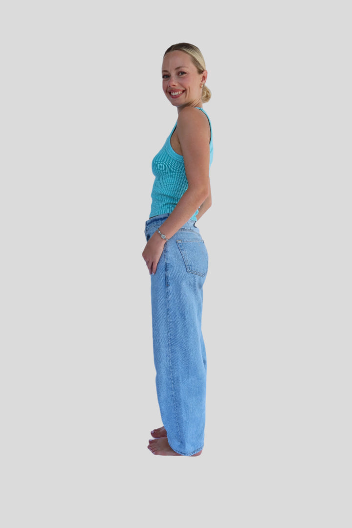 Person wearing a tank and blue jeans on a white background