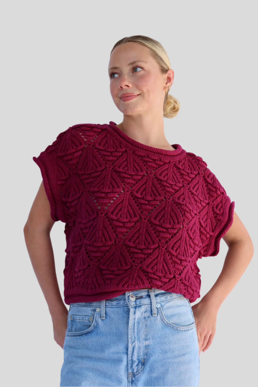 Woman wearing a knitted top with a geometric pattern against a neutral background