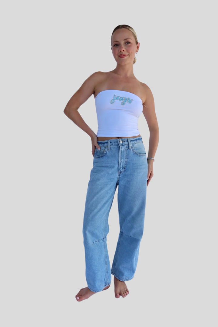 Woman wearing a strapless top with 'jags' text and high-waisted jeans on a light background
