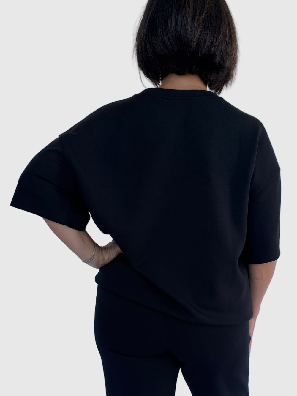 Person wearing a black outfit on a light background