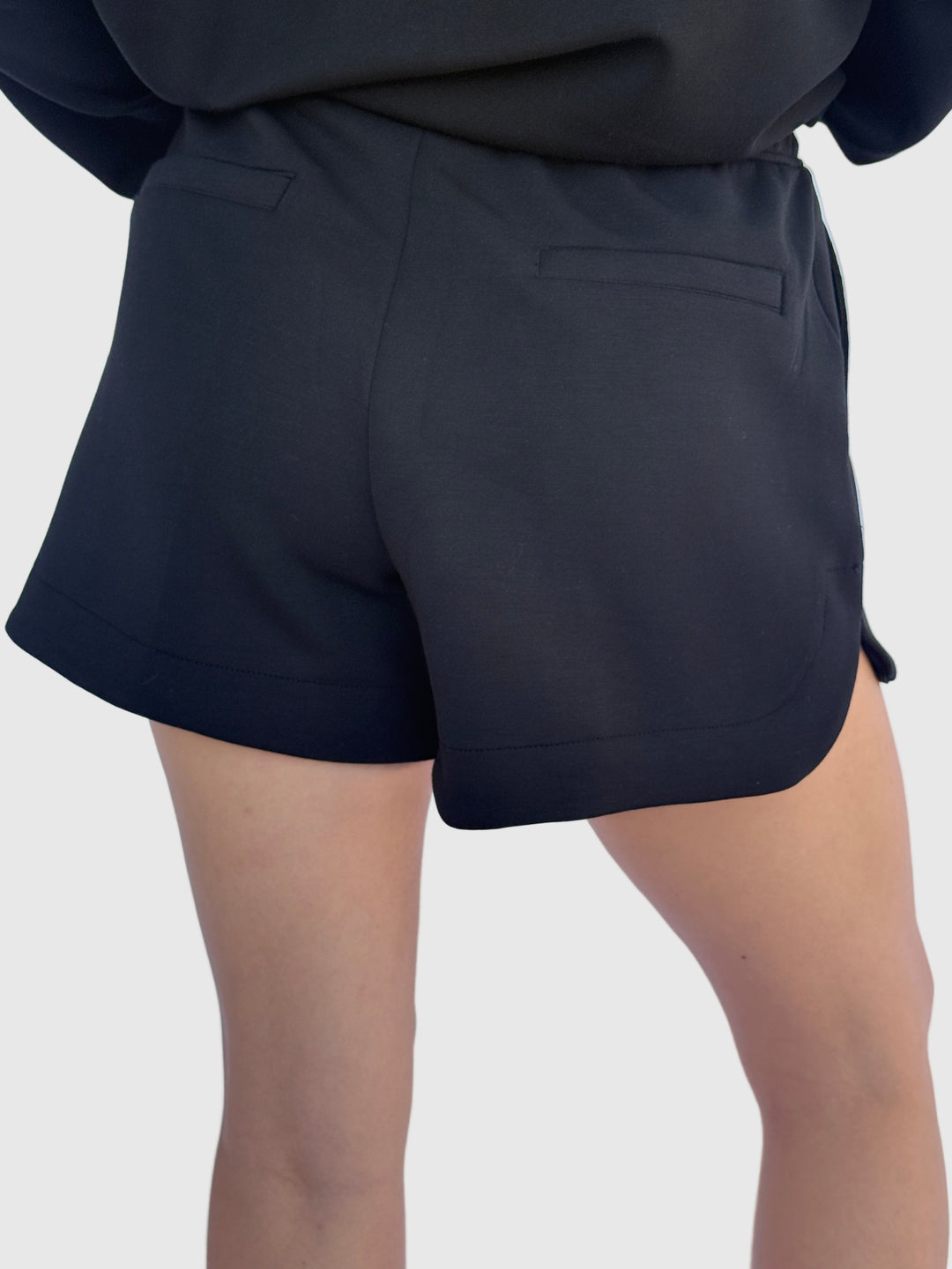 Person wearing black shorts with a light background