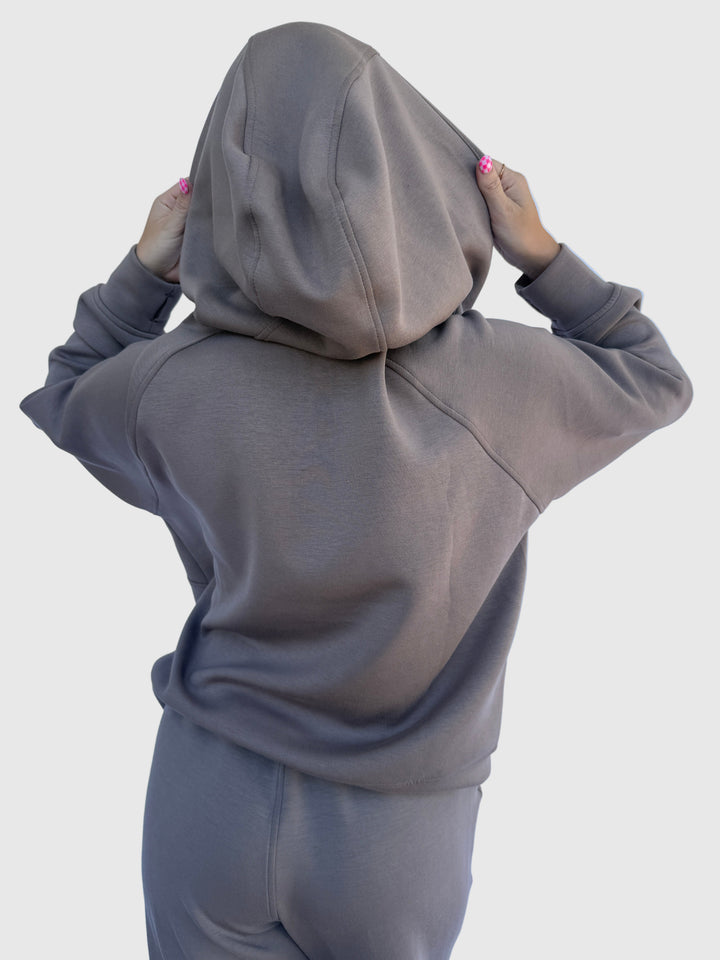 Person wearing a gray hoodie against a light background