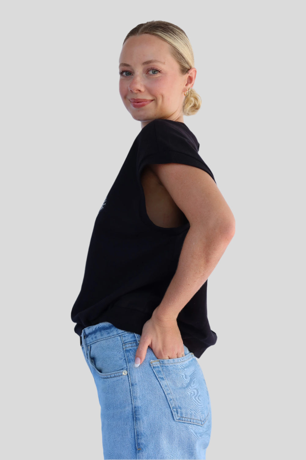 Person wearing a black top and blue jeans against a light background
