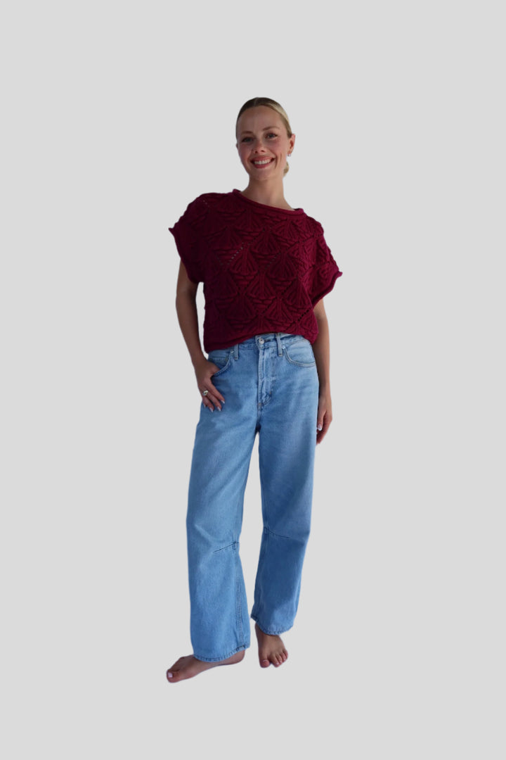 Person wearing a sweater and blue jeans on a white background