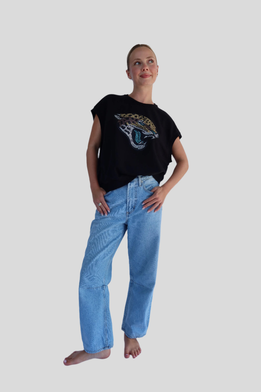 Person wearing a black shirt with a Jaguar graphic design and light blue jeans on a white background