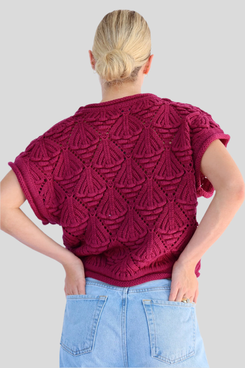 Person wearing a knitted sweater against a light background