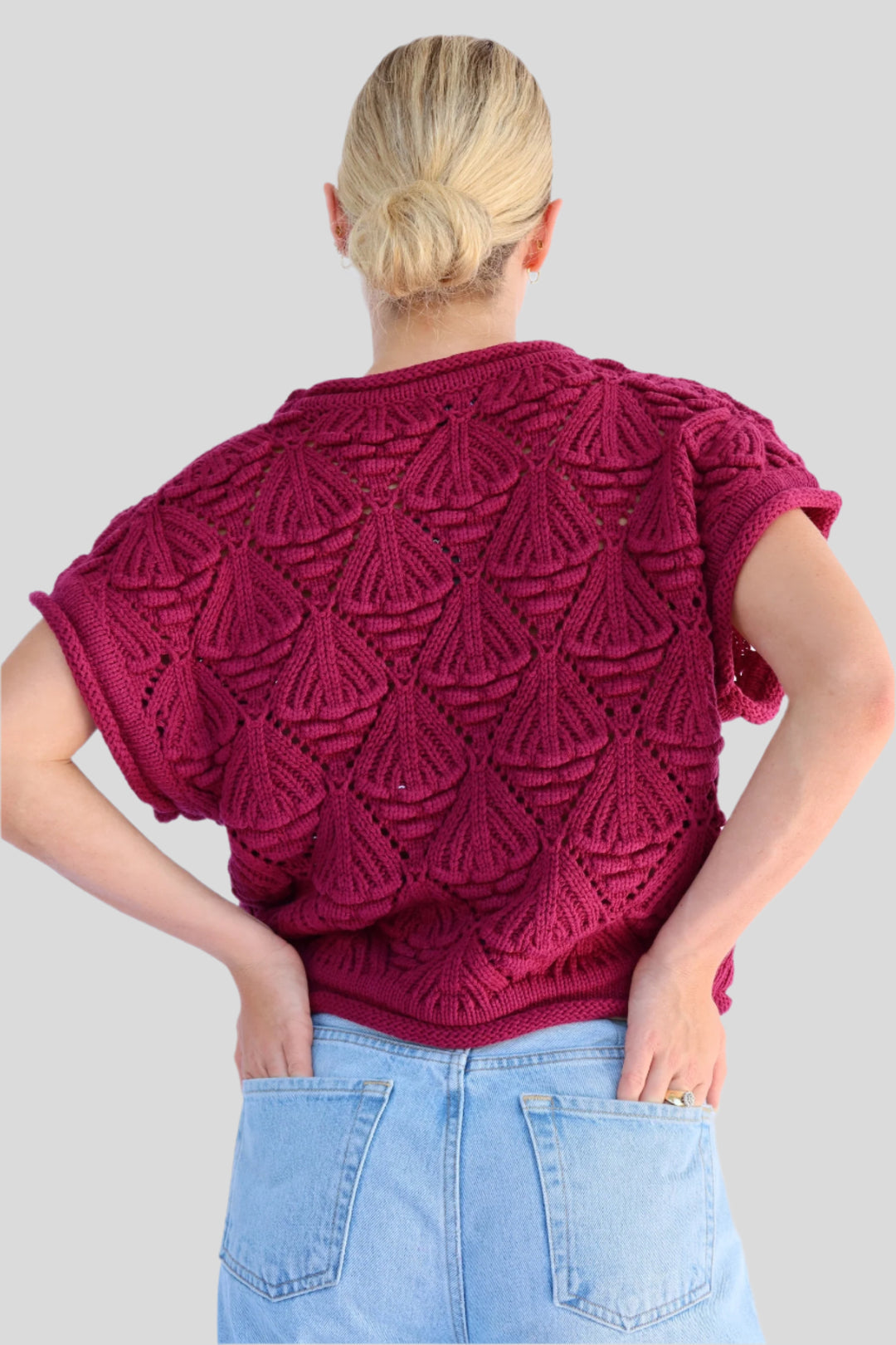 Person wearing a knitted sweater against a light background