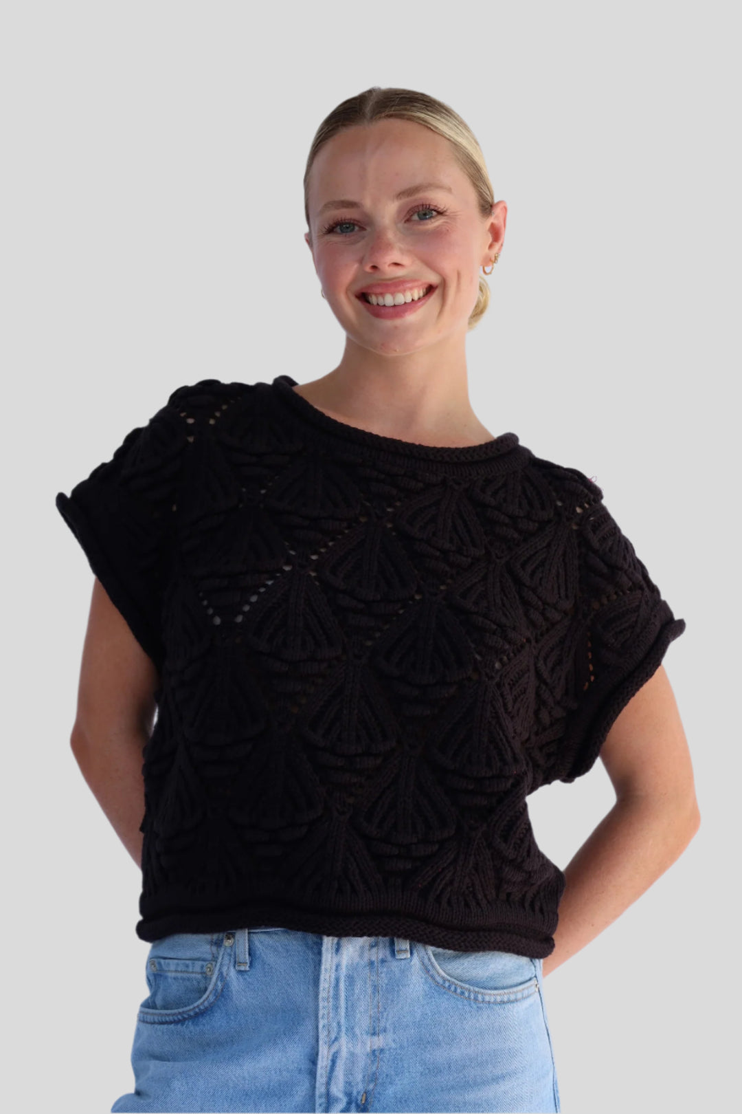 Woman wearing a black knitted top with a pattern against a light background