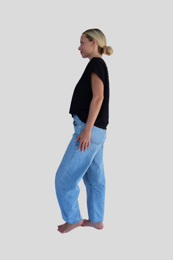 Person wearing a black top and light blue jeans against a white background