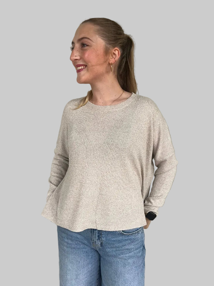 Person wearing a tan knit top and blue jeans.