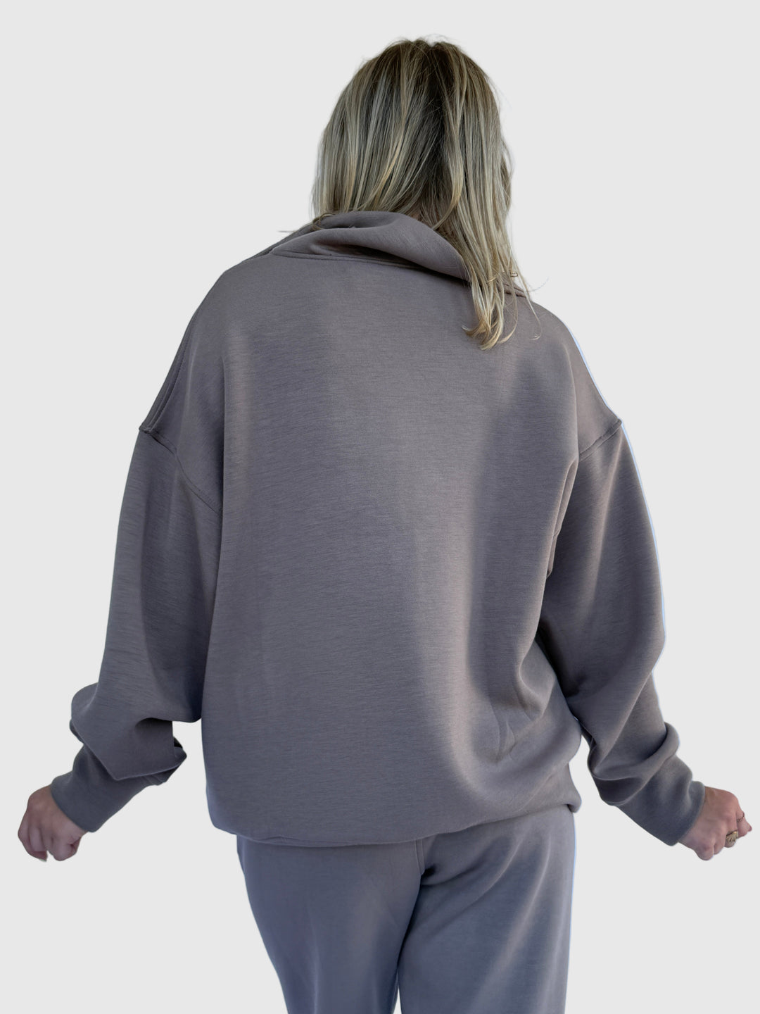 Person wearing a gray hoodie against a light background
