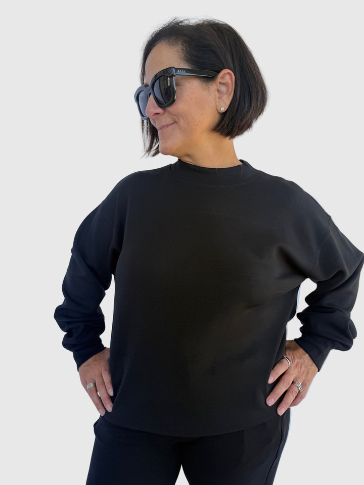 Person wearing a black sweatshirt against a light background